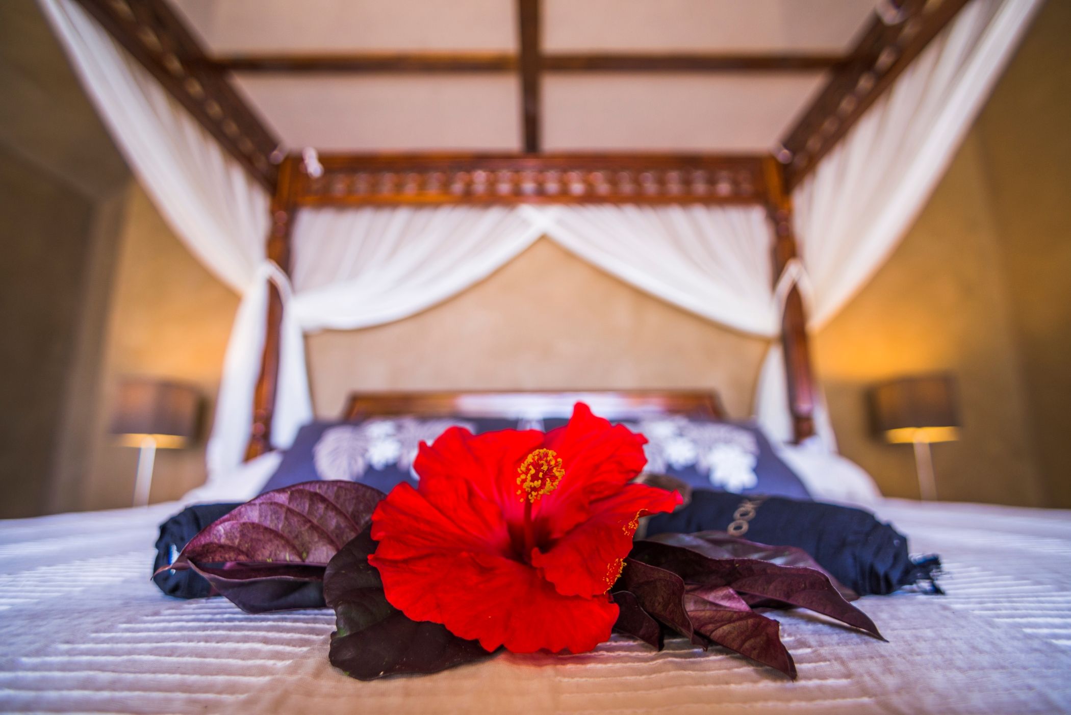 Luxury accommodation hotel bedroom details of a four poster bed and red flowers in Costa Rica.
