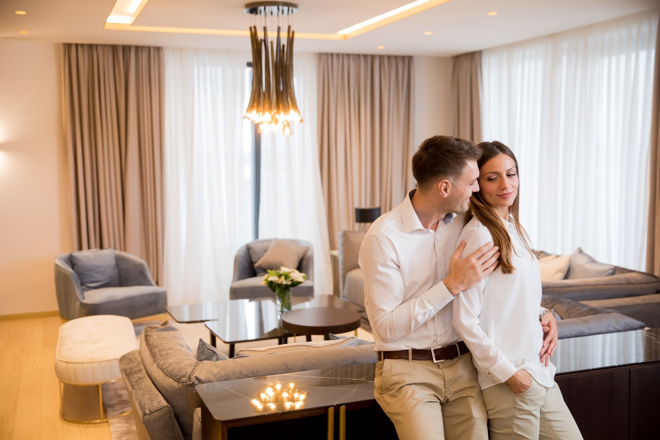 Couple embracing standing in living room of a contemporary hotel suite.