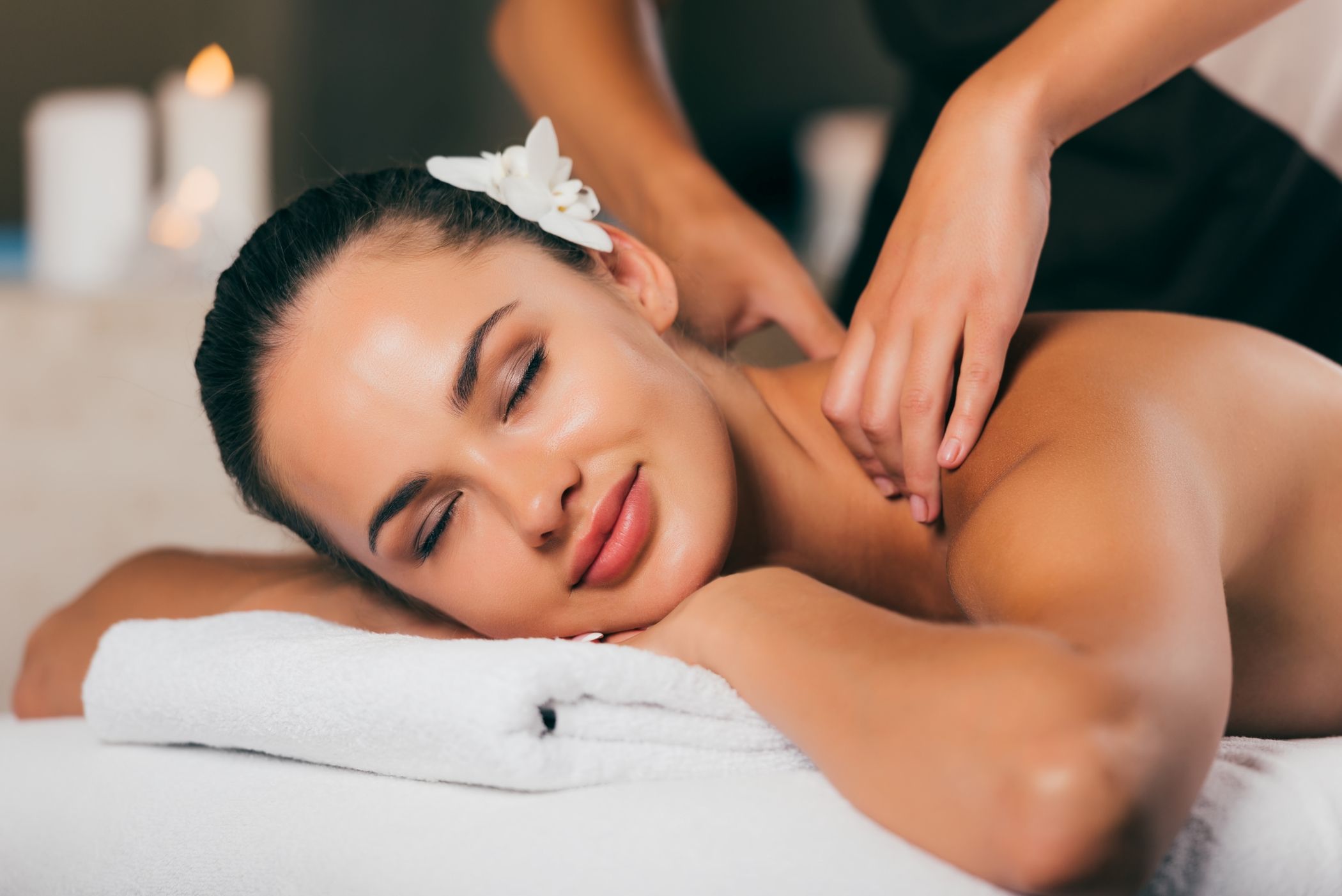 Beautiful dark haired woman with her eyes closed enjoying a professional massage at spa in Miami.