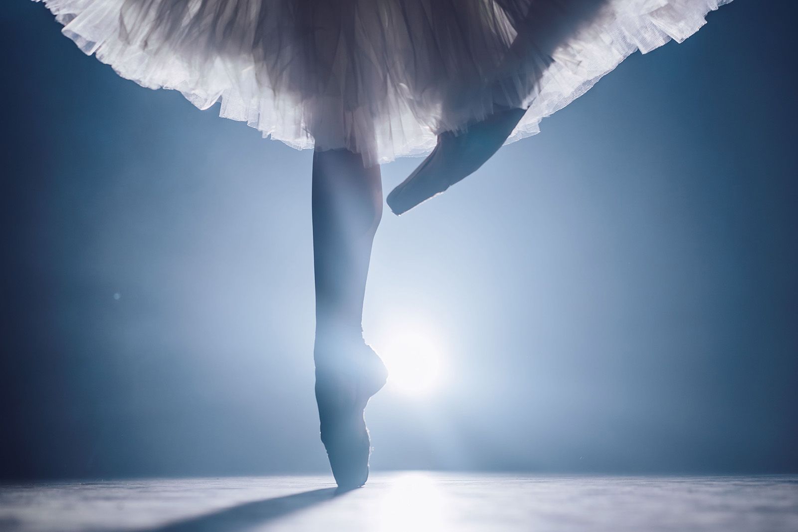 Ballet dancer performing on pointe under stage lights, capturing the grace and elegance of a live ballet performance in Miami.
