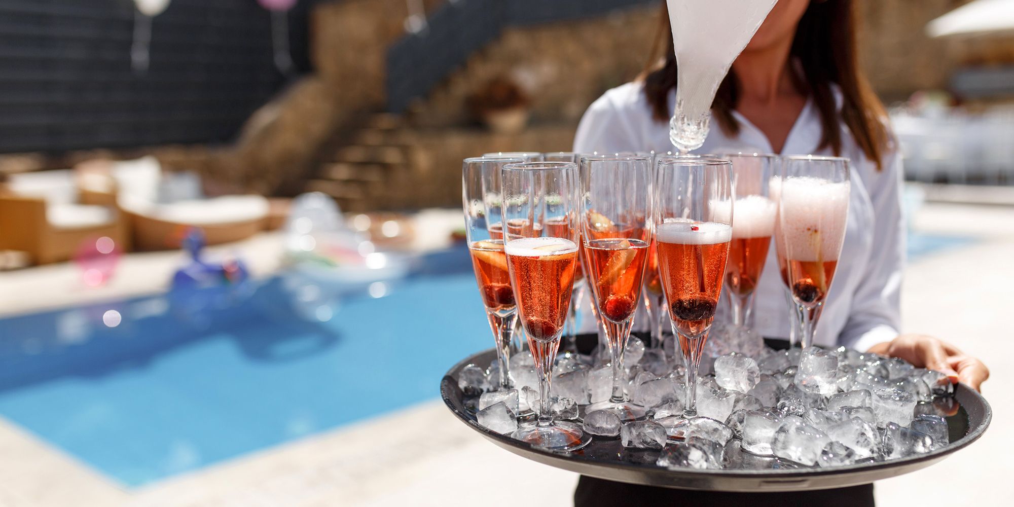 A server holds a tray of champagne at a poolside Luxuri villa in Miami for a private event for Art Basel Miami Beach.