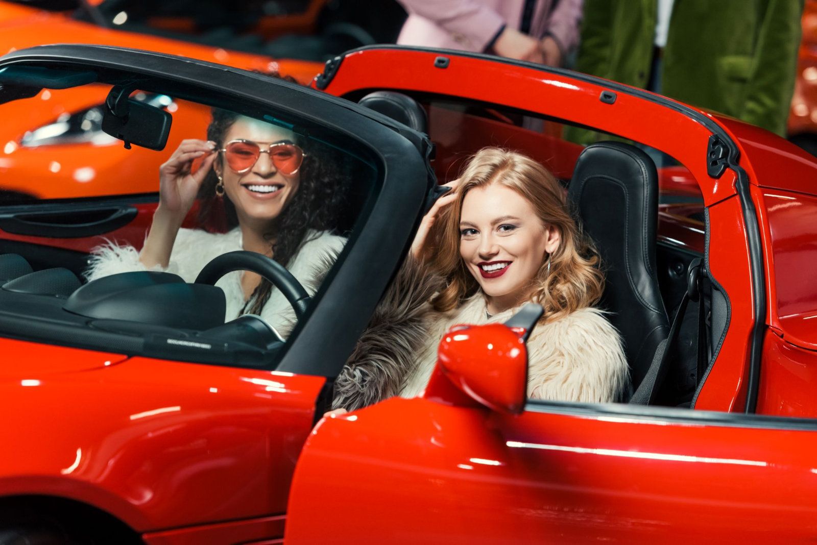 Two fashionable smiling multiethnic women sit in a Ferrari in Miami.