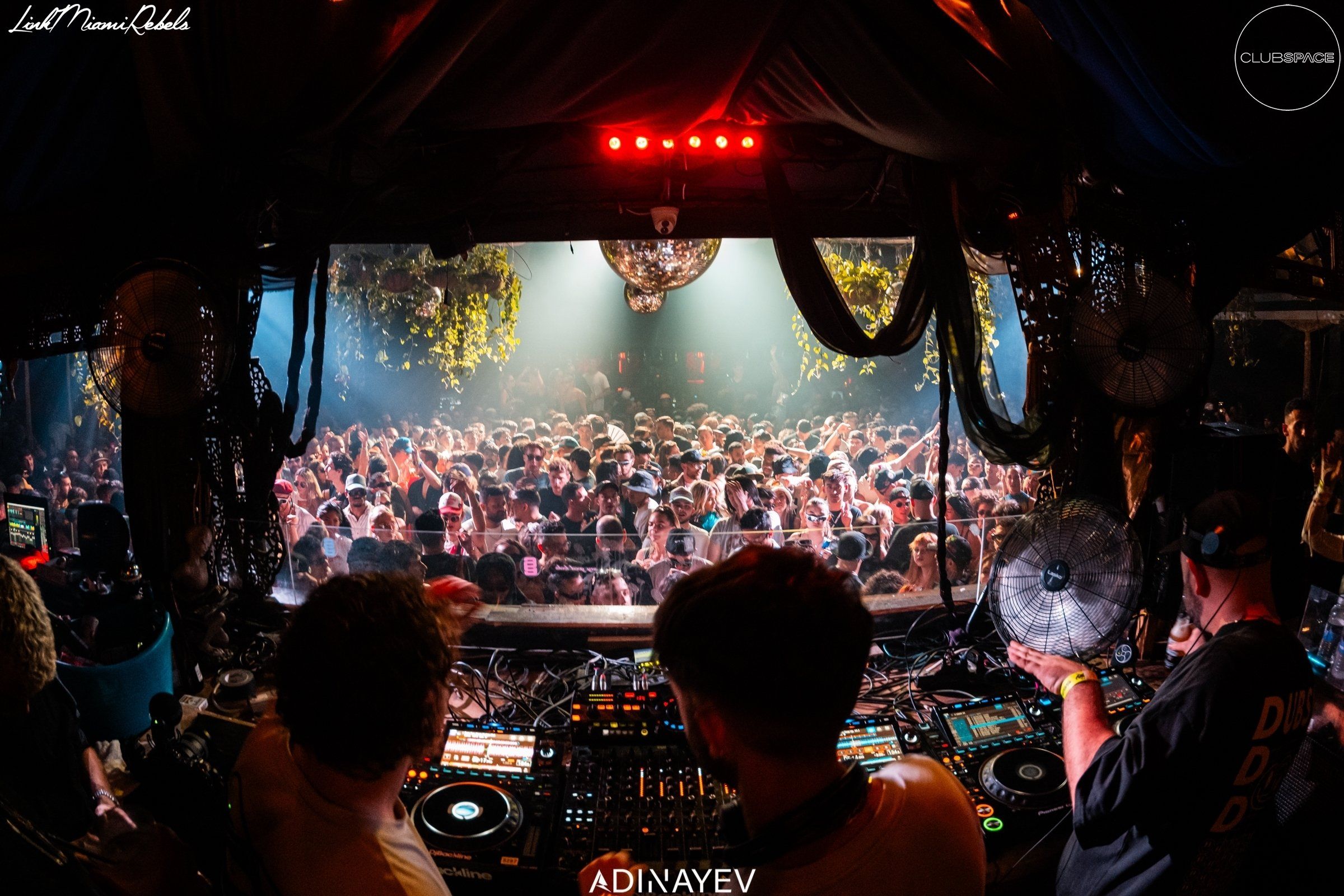 A DJ set view at Club Space, with the DJ in focus and a massive crowd dancing and enjoying the music in the background.